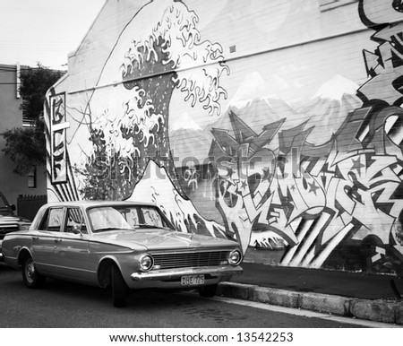 Black and white shot of car and graffiti strewn wall