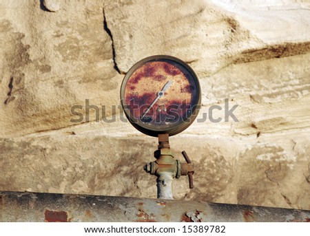 a rusted gauge sits atop a rusted industrial pipe