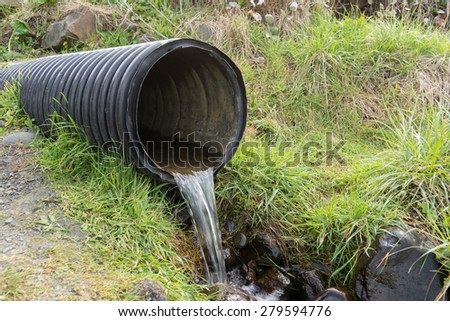 Street water drainage pipe emptying water out into nature.
