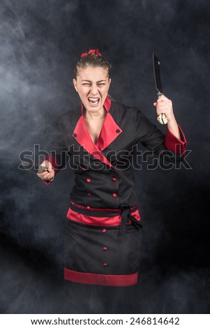 Crazy chef screaming and attacking with her weapons knife and chopping knide between smoke and fog
