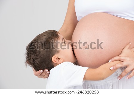 Mother and son together; while kid kisses her pregnant mothers belly, mommy  fondles and caress him