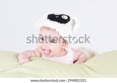 Portrait of little baby girl with cute expression and lamb hat lying on pillow