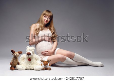 Pregnant belly. Woman expecting a baby with a cute teddy bears, toys