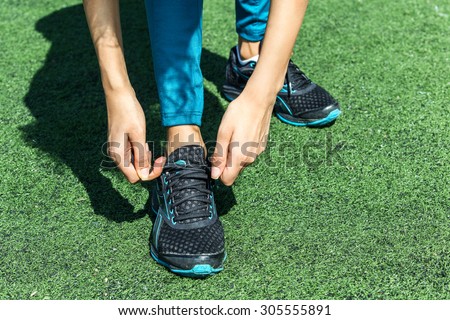 Getting ready for a run. Runner feet running on road closeup on shoe. woman fitness  jog workout . tie shoelaces
