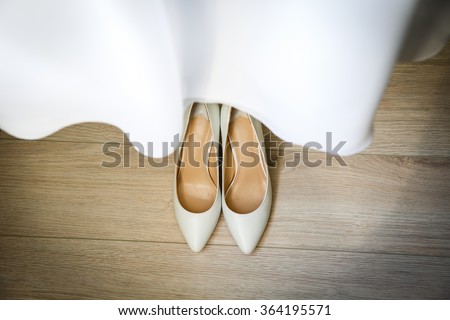 white wedding shoes with dress. Cute stylish beige high heels with a bow on the background room, fashion, wedding. Morning bride.