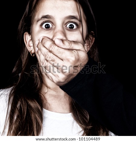 Portrait of a scared girl being abused by an adult man who covers her mouth with his hand (only his hand is visible, the rest is hidden in the shadows)