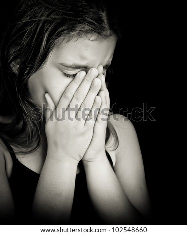 Emotional black and white portrait of a girl crying isolated on black with space for text