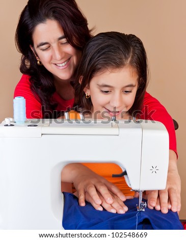 Hispanic mother  and her daughter using a sewing machine and sharing a good time together