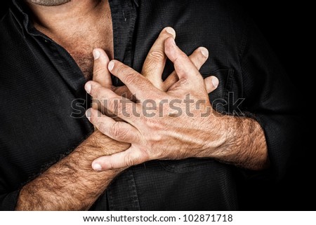 Close up of two hands grabbing a chest on a black background, useful to represent a heart attack or any sentimental concept