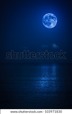 Bright full moon with reflections on a calm ocean at midnight