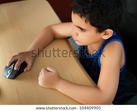 Small hispanic boy working on a computer or browsing the web at home photographed from above