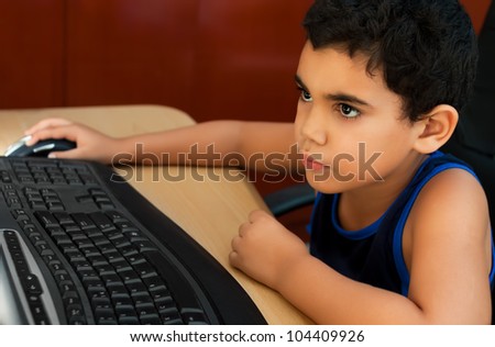 Small latin boy working on a computer or browsing the web at home