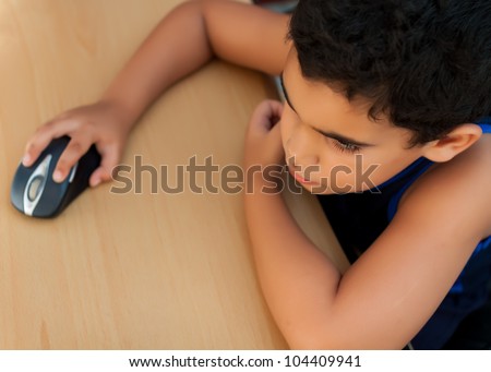 Small latin boy working on a computer or browsing the web at home photographed from above