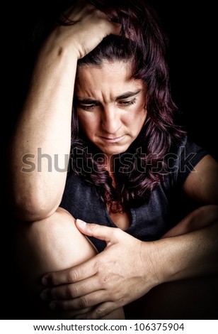 Woman suffering from a very strong depression with a very sad face on a black background