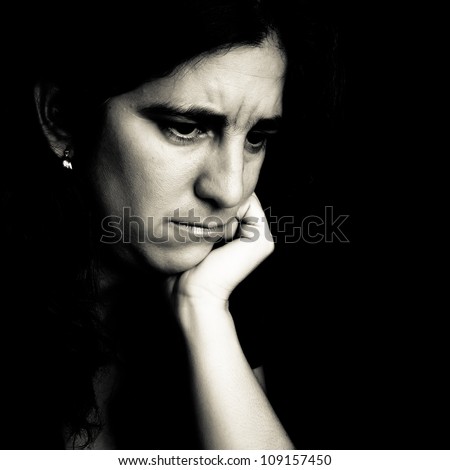 Dramatic black and white portrait of a worried young woman on a black background
