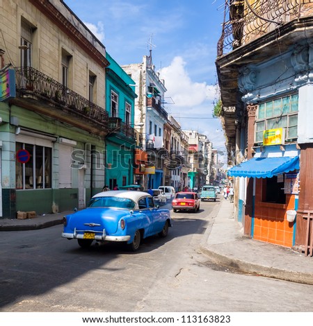 HAVANA-SEPTEMBER 13:People and old cars in a central street September 13,2012 in Havana.With 2.4 million inhabitants in the city and 3.7 in its urban area,Havana is the largest city in the Caribbean