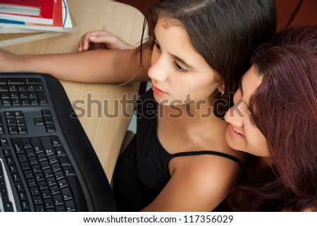 Hispanic girl working on a computer or browsing the web while her mother watches what she is doing