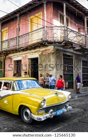 SANTIAGO DE CUBA,CUBA-JANUARY 11:Old Buick next to crumbling buildings January 11,2013 in Santiago de Cuba.Thousands of these classic cars are used as taxis and private vehicles across the country