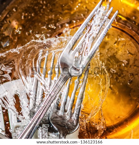 Silverware and glass dishes washed with splashing water