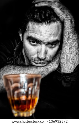 Black and white grunge portrait of a drunk and depressed hispanic man (with a contrasty golden alcoholic drink)