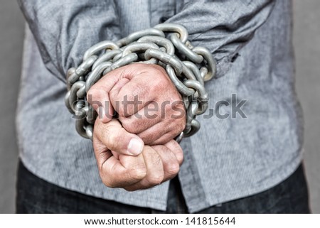 Elegant man with his hands chained with strong steel chains and a padlock