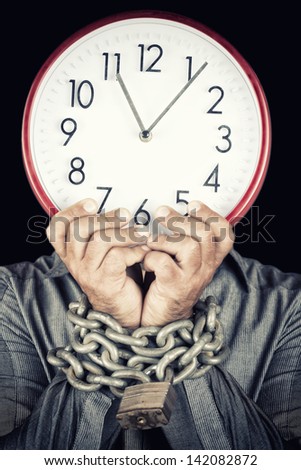 Formally dressed man holding a clock in place of his face with his hands chained with a metallic chain and padlock (useful to illustrate overworked  or stressed people) (isolated on white)