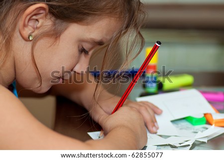 Little girl working on her art project with art materials on the table