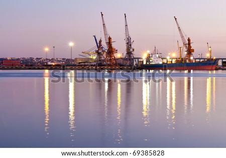 Commercial docks at sunset with a ship and cranes