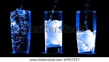 Water being served in three tall glasses isolated on a black background
