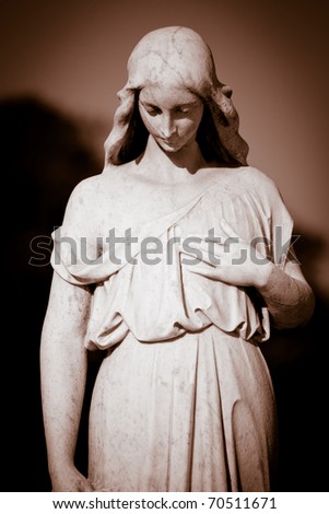 Ancient marble statue of a young woman wearing robes in sepia tones