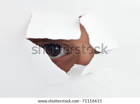 An  child\'s eye looking through a hole in a  white sheet of paper