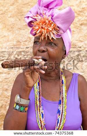 HAVANA-MARCH 28:Woman with typical clothes and a huge cuban cigar on March 28,2011 in Havana.People dress in a way that represents the cuban nationality can be found in the streets of Old Havana