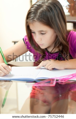 Vertical shot of a small girl wearing shorts and a t-shirt working on her school project at home