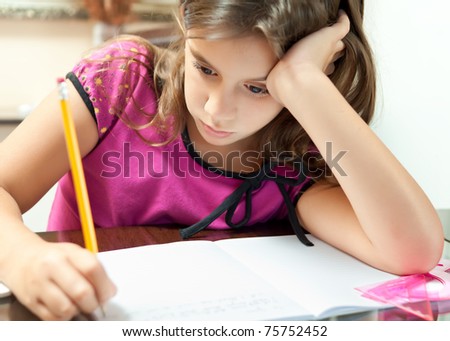 Small girl looking bored while working on her school project at home
