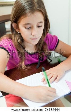 Beautiful small girl working on her school project at home