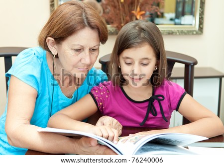 Hispanic grandmother and granddaughter reading an illustrated  book