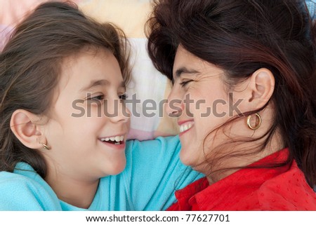 Beautiful latin mother and daughter smiling with love at each other