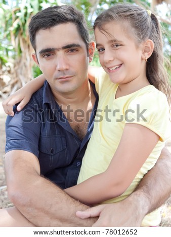 Portrait of a latin father hugging her daughter at a park