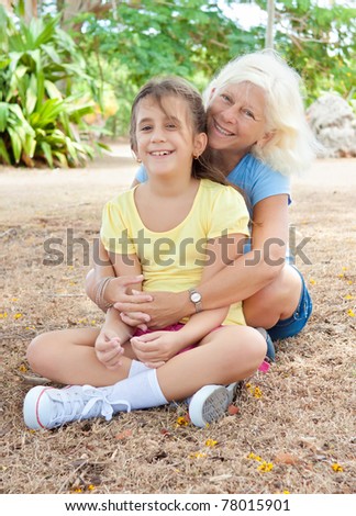 Latin grandmother hugging her adorable granddaughter with a smile