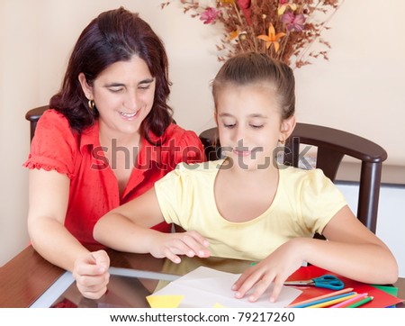 Latin mother and daughter working on an art project at home with some art supplies on the table