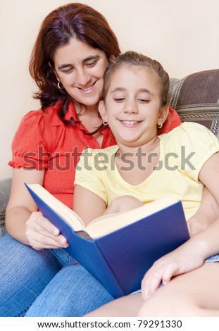 Latin mother and daughter reading a book together