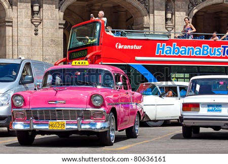 HAVANA-JULY 6:Touristic sightseeing bus with an old Chevrolet in the foreground July 6,2011 in Havana. More than 2 million tourists visit the island yearly attracted by its distinct culture