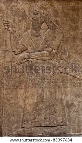 Ancient assyrian clay relief depicting a warrior with a sword and text written in cuneiform writing