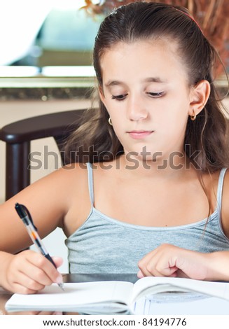 Adorable small latin girl working on her school project at home