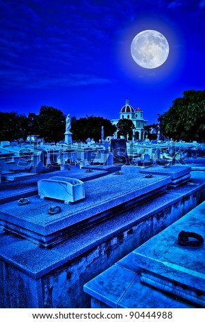 Scary old cemetery at night with a bright full moon shining over the graves