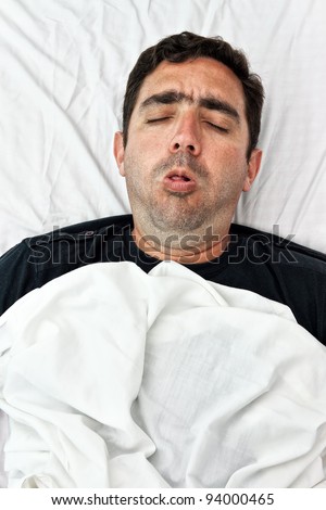Portrait of a sick hispanic man laying in bed and coughing