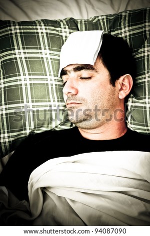 Dramatic desaturated image of a sick man laying in bed with fever