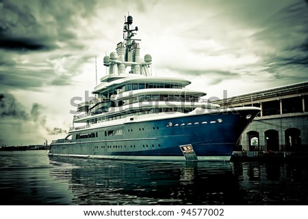 Grunge image of a modern scientific research or tourism ship docked in a pier with a violent storm approaching