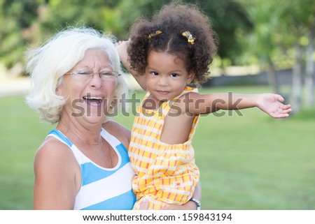 Latin girl and her caucasian grandmother hugging and having fun in a park
