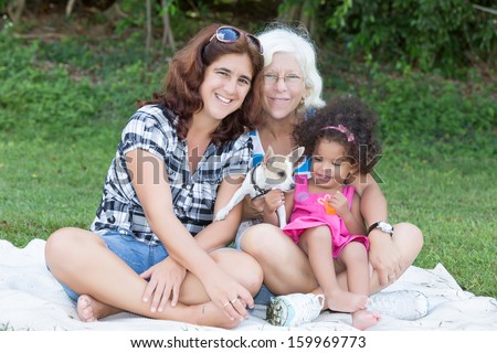 Happy latin family camping on a park (including grandmother, mother, daughter and a small dog)